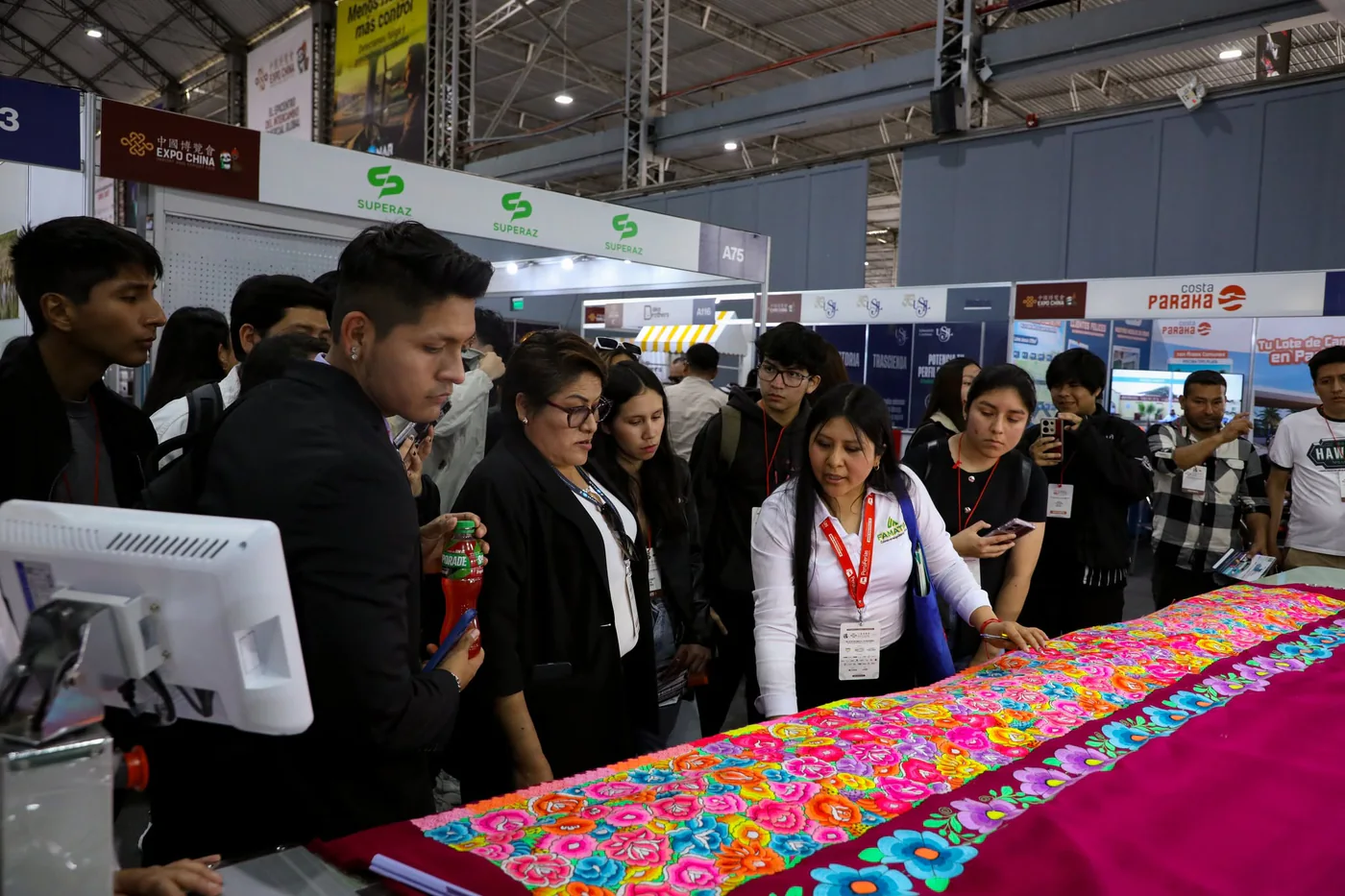 Visitantes revisando un bordado recién hecho en la feria